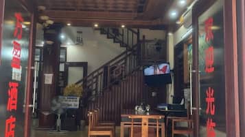 A hotel lobby with a staircase, wooden furniture, and a television screen.
