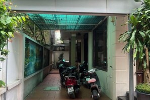 A narrow corridor with parked scooters, a tiled floor, and a green awning. - HOANG HA VILLA (Bac Ninh)