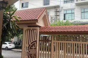 Un cancello con un design tradizionale, un tetto in tegole rosse e un edificio sullo sfondo.