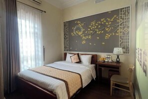 A hotel room with a bed, bedside table, lamp, and a chair. - HOANG HA VILLA (Bac Ninh)