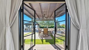 Avattavat lasiliukuovet johtavat ulkotilalle, jossa on patio, pergola, istuimia ja nurmikko.