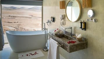 A bathroom with a freestanding bathtub, a vanity with a marble countertop, and a large mirror.
