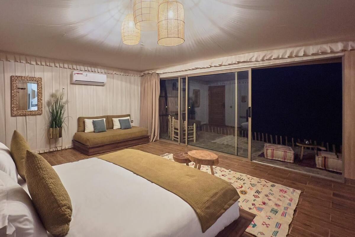 Ein Schlafzimmer mit einem großen Bett, einer Couch, einem kleinen Tisch und einem Balkon mit Blick.