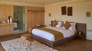 A bedroom with a large bed, wooden headboard, and a bedside table with a lamp. - Stellar Agafay Desert Camp (Gmassa)
