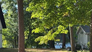 A house with a dock extending into a lake, surrounded by trees and a grassy area. - Great room w/ pool table in a 1-bdrm party barn in Newaygo; River access (Newaygo)