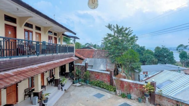 A two-story building with a balcony, outdoor seating, and a view of a residential area. - ARBA Artana & Chipsari Hotel Pangalengan (Pangalengan)