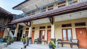 A building with a balcony, wooden doors, and outdoor seating. - ARBA Artana & Chipsari Hotel Pangalengan (Pangalengan)
