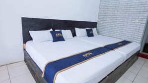 A hotel room with a bed, white bedding, and a blue and gold bed runner. - ARBA Artana & Chipsari Hotel Pangalengan (Pangalengan)
