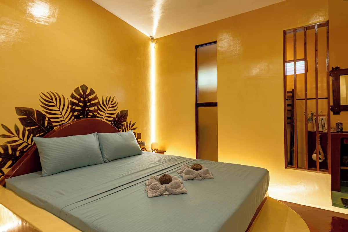 A bed with a light blue bedspread, two pillows, and two towels shaped like turtles.