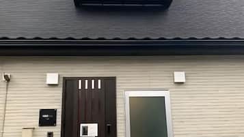 A building with a dark brown door, a white door, and a small sign on the wall.