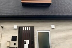 A building with a dark brown door, a white door, and a small sign on the wall. - Male Only H2O Stay Ōtorii (Tokyo)