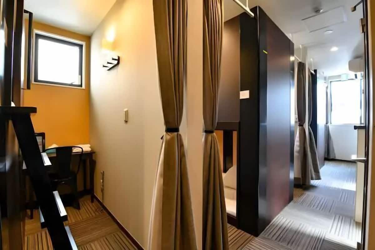 A hotel corridor with a staircase, a window, and a door leading to a room.