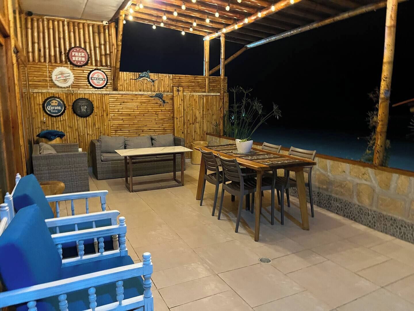 An outdoor patio area with a wooden table and chairs, a sofa, and a blue chair.