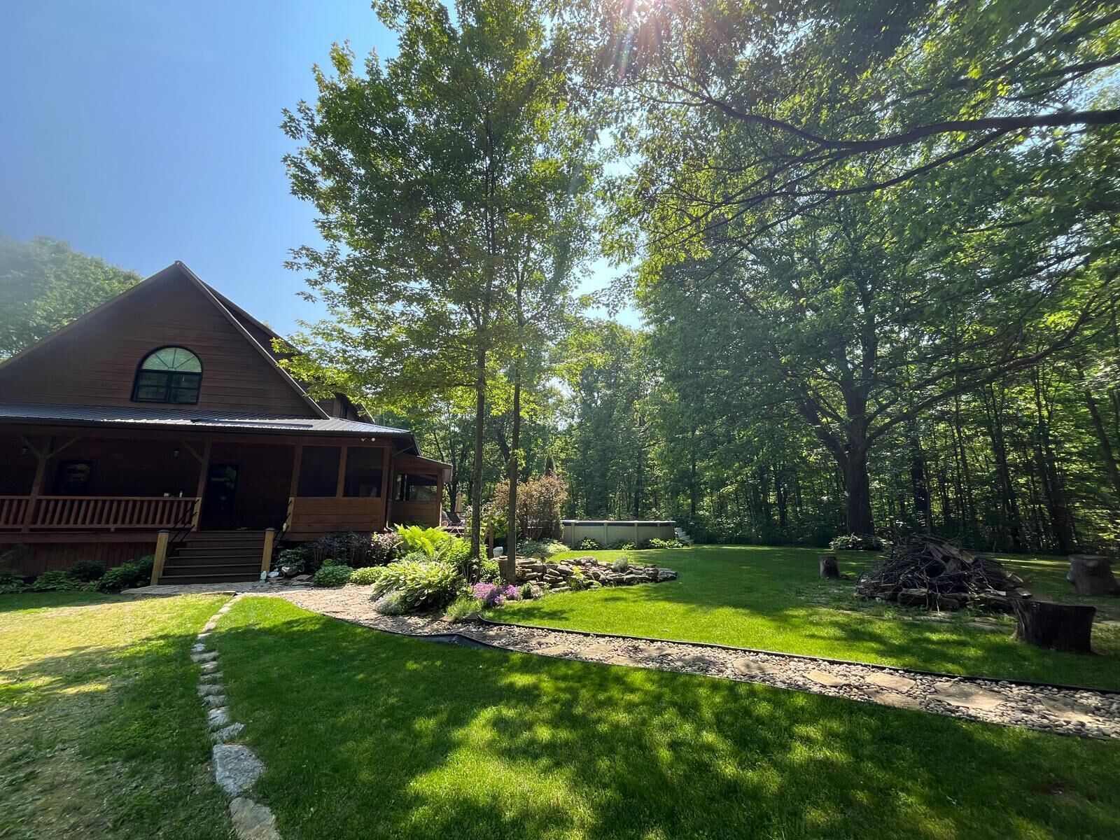 A rustic cabin with a porch, surrounded by lush greenery and a well-maintained lawn.
