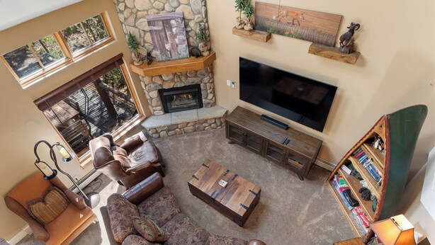 A cozy living room with a stone fireplace, leather furniture, a flat-screen TV, and a bookshelf. - Sf1975-4 (Keystone)