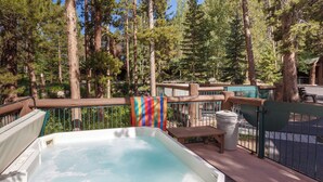 A hot tub on a deck with a wooden railing, surrounded by tall trees. - Sf1975-4 (Keystone)