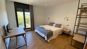 A bedroom with a large bed, bedside tables, a desk, and a wardrobe. - Hostal Mussols (Poboleda)