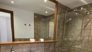A modern bathroom with a large mirror, a sink, a toilet, and a glass-enclosed shower. - Hostal Mussols (Poboleda)