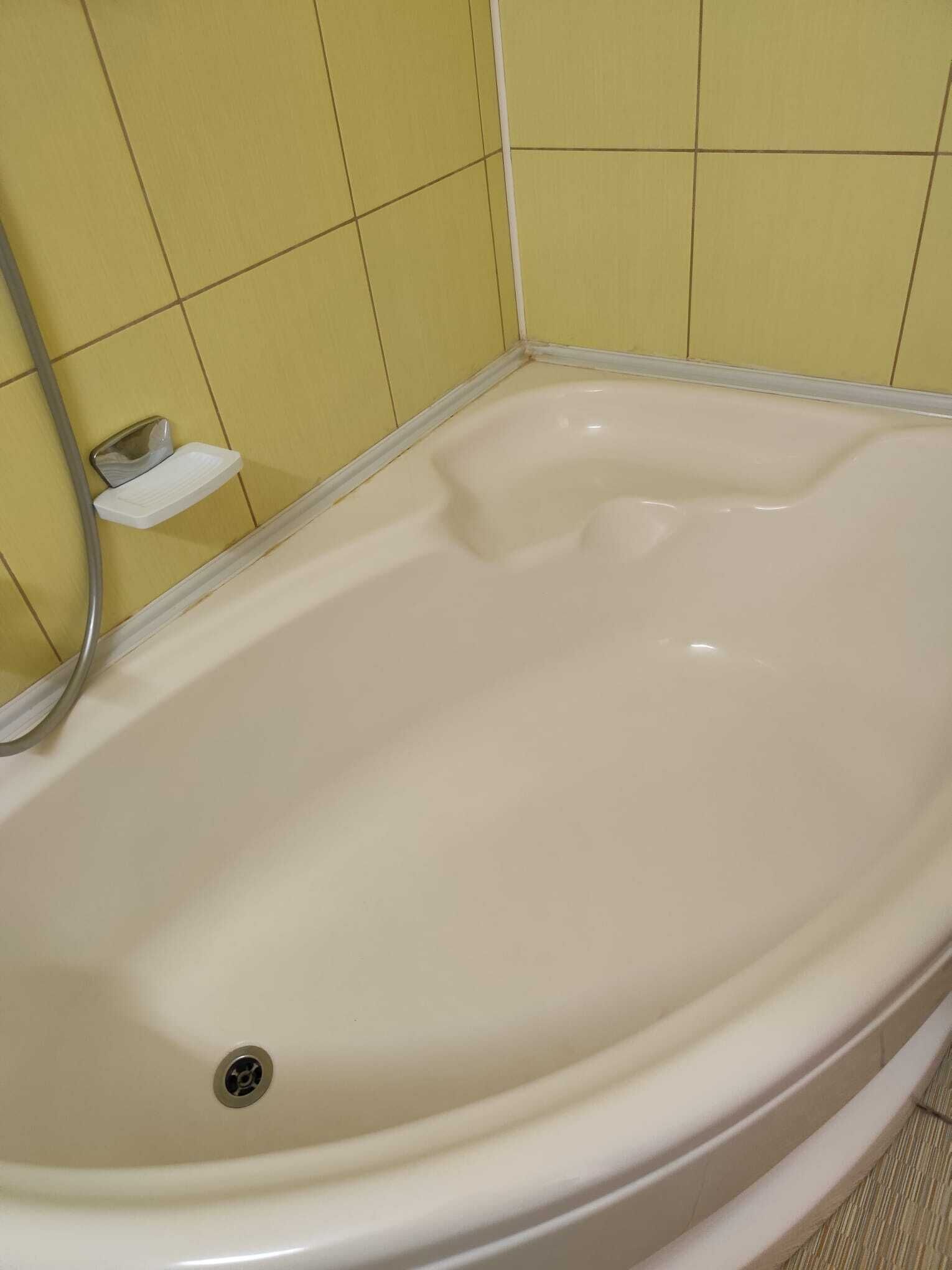 Une baignoire avec un drain, une douchette et une petite étagère.