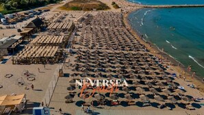 A beach with numerous umbrellas and sun loungers, a sandy shore, and a clear view of the sea. - Traian Residence Constanța (Constanța)