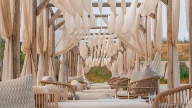Een terras met rieten meubilair en een pergola.