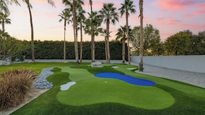 A well-maintained golf course with a putting green, sand bunkers, and a water hazard.