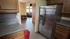 A kitchen with wooden cabinets, a stainless steel refrigerator, and a red trash bin. - Charming 1-bedroom house in enjoyable Milan with AC (Milan)