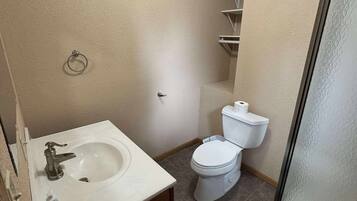 Et lille badeværelse med vask, toilet og bruseområde.