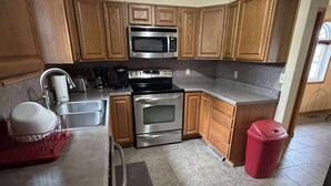 A kitchen with wooden cabinets, a stainless steel microwave, an oven, and a sink. - Charming 1-bedroom house in enjoyable Milan with AC (Milan)