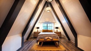 A bedroom with a sloped ceiling, a bed with a headboard, bedside tables, and a window. - Gorgeous A Frame on 18 private acres.  (Oneonta)