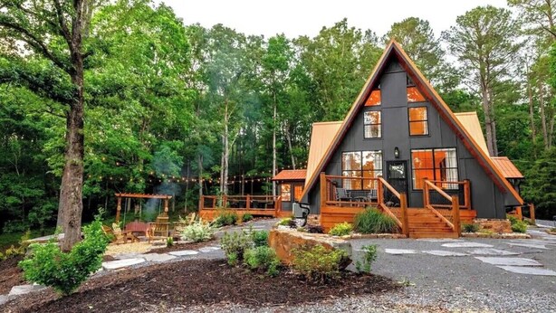 A cabin with a triangular roof, wooden deck, and a stone pathway leading to the entrance. - Gorgeous A Frame on 18 private acres.  (Oneonta)