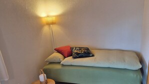 A small, cozy room with a green sofa, a small wooden table, and a wall-mounted lamp. - Cozy vacation apartment - nature & relaxation (Aeschi bei Spiez)