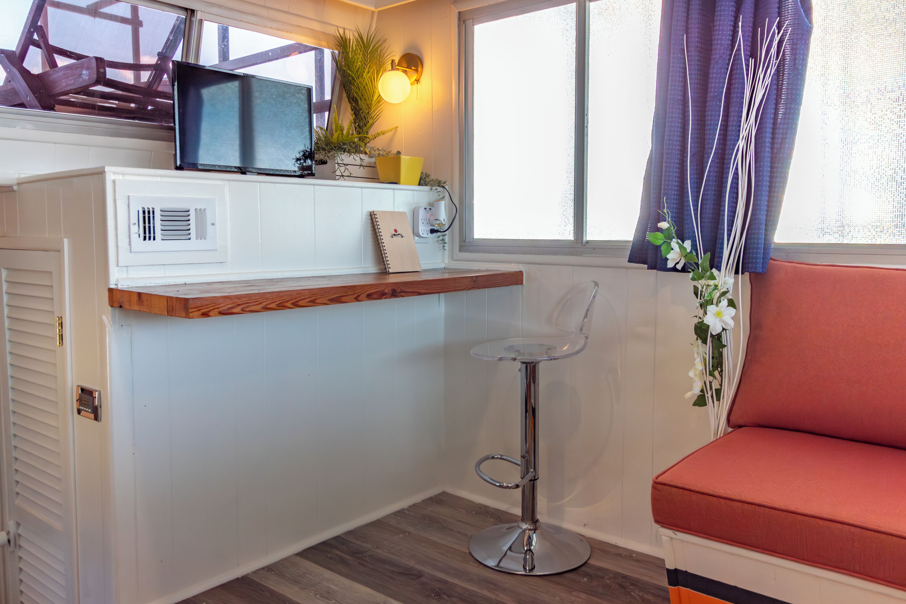 A compact kitchen with a microwave, a small shelf, and a bar stool.