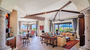 A spacious living area with a stone floor, a dining area with a bar, and a view of the outdoors.