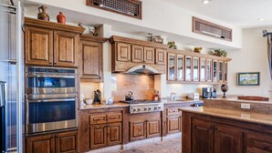 A kitchen with wooden cabinets, stainless steel appliances, and a stone backsplash.