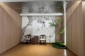A room with a wooden floor, a marble wall, two chairs, a small table, and a plant. - Nipponbashi Royal (Osaka)