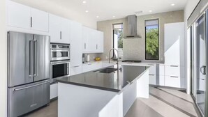 Een moderne keuken met witte kasten, roestvrijstalen apparatuur en een groot eiland.
