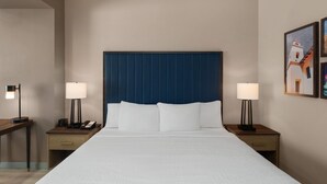 Ein Hotelzimmer mit einem großen Bett, zwei Nachttischen mit Lampen, einem Telefon und einem Bild an der Wand.