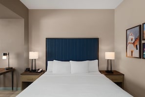 A hotel room with a large bed, two bedside tables with lamps, a telephone, and a painting on the wall. - La Quinta Inn & Suites By Wyndham Tracy (Tracy)