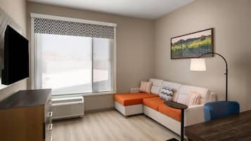 Una sala de estar moderna con un sofá modular, un televisor de pantalla plana, una lámpara de pie y un amplio ventanal con vistas a un viñedo.