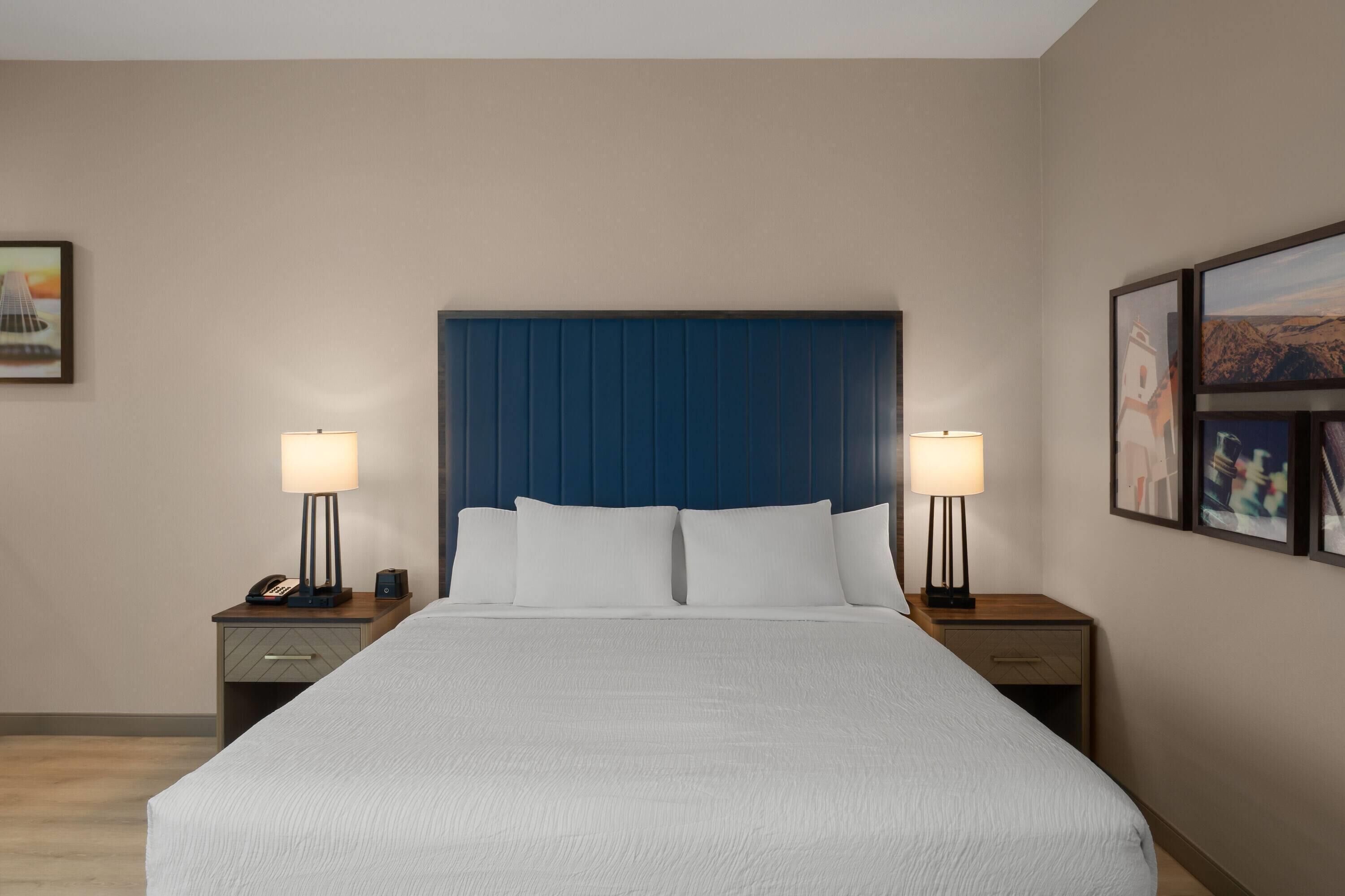 A hotel room with a large bed, two bedside tables, and a headboard.