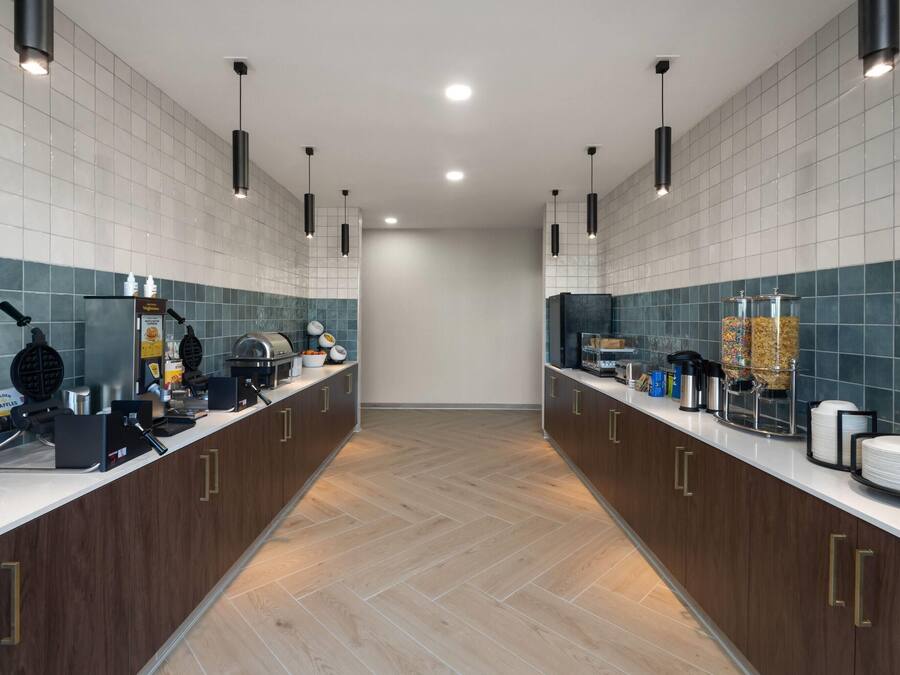 A modern kitchen with two waffle makers, a coffee machine, and a variety of food items on the counter.
