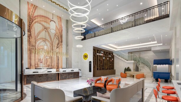 A spacious lobby with a reception desk, seating area, and a staircase leading to an upper level.