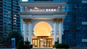 The exterior of a hotel with a grand entrance, columns, and a sign indicating a parking area.
