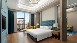 Een moderne hotelkamer met een groot bed, een bank, een televisie en uitzicht op de stad.