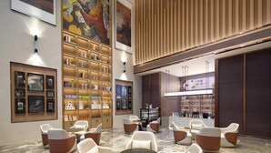 A modern lobby with seating areas, a coffee bar, and a large mural on the wall. - Wingate By Wyndham Puer Tea Horse Ancient Town (Baoding)