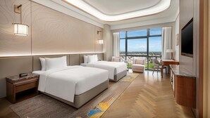 Una habitación de hotel moderna con dos camas, un escritorio, un televisor y vista a la ciudad.