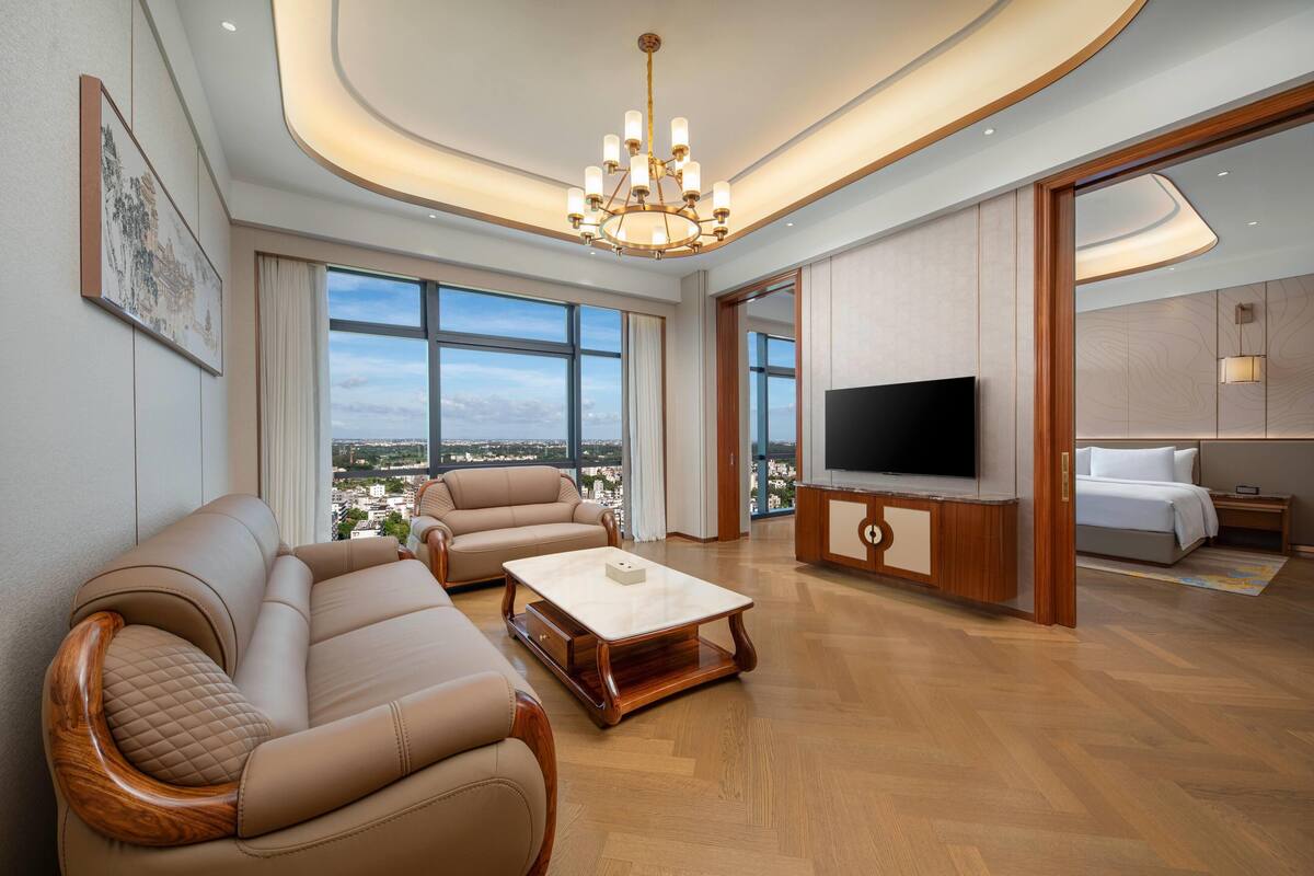 Un salón amplio con televisor grande, asientos cómodos y vista a la ciudad.