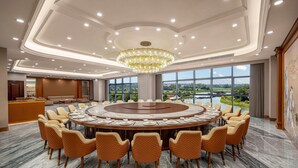 Un salón de conferencias con una mesa redonda, sillas color beige y un candelabro.