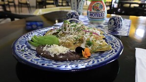A plate of food with a decorative blue and white pattern, a bottle labeled "HOTELES", and a small decorative item on the table.